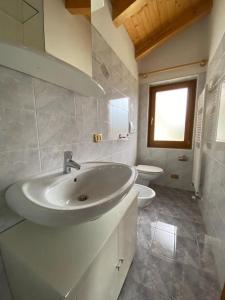 a white bathroom with a sink and a toilet at Appartamento da Fabio - nel cuore delle Dolomiti in Danta