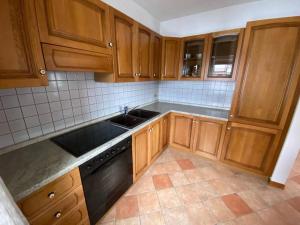 eine Küche mit Holzschränken und einem schwarzen Geschirrspüler in der Unterkunft Appartamento da Fabio - nel cuore delle Dolomiti in Danta