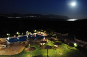 a pool with tables and umbrellas at night at Simosmare Resort in Elafonisos