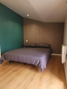 a bed in a bedroom with a green wall at Maison Cosy Rénovée - Puy du Fou in Saint-Laurent-sur-Sèvre