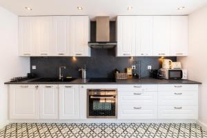 a white kitchen with white cabinets and appliances at La maison Grand Cru in Arveyres +6 photos
