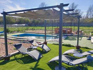 um grupo de cadeiras de jardim sob um dossel ao lado de uma piscina em Finca Arroyo del Valle em San Andrés del Rabanedo