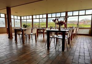 a dining room with tables and chairs and windows at Landhuis Bovenste Bos in Epen