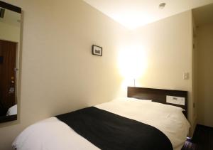 a bedroom with a bed with a black and white blanket at APA Hotel Tokyo Kiba in Tokyo