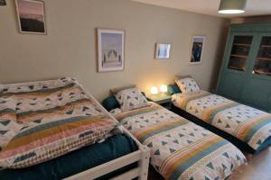 a bedroom with two beds and a green door at Le Grand Bourgeois in Appoigny