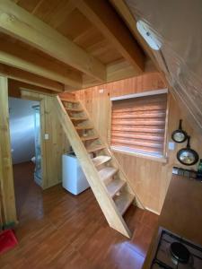 una escalera de madera en una casa pequeña con ventana en Cabaña Ataraxia (RDS), en Riñinahue