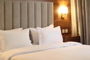 um quarto com uma cama com lençóis brancos e almofadas em شرفة em Riade