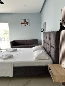 a bedroom with a large bed with a gray headboard at Summer Gate Hotel in Ksamil