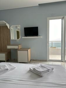 a white bedroom with a bed and a television at Summer Gate Hotel in Ksamil