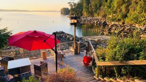 a red umbrella sitting on a boardwalk next to the water at SeaLaVie Rare Peaceful & Hidden Gem Shore House in Ladysmith