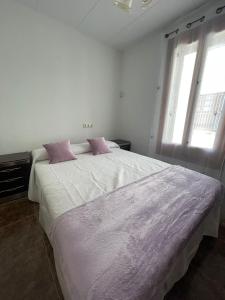 1 dormitorio blanco con 1 cama grande con almohadas rosas en Lo Jardí de Benifallet en Benifallet
