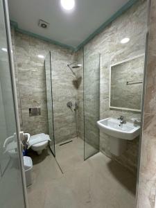 a bathroom with a shower and a sink and a toilet at Summer Gate Hotel in Ksamil