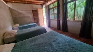two beds in a room with two windows at Hostal El Nawal in Lanquín