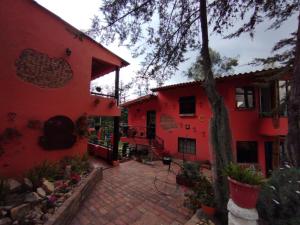 ein rotes Haus mit einem gemauerten Innenhof davor in der Unterkunft Hotel Estancia Cucunuvaca in Cucunubá