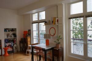 a living room with a table and two windows at Double appartement - Le Marais in Paris