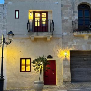 a building with a red door and windows and a street light at Townhouse 7 in Dingli