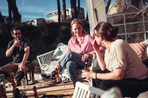 a group of people sitting on a porch with drinks at The Glamping Spot - Douarnenez in Plonévez-Porzay
