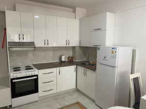 a kitchen with white cabinets and a white refrigerator at srle home in Skopje