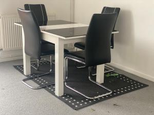 a white table with four black chairs around it at Stopin in Crawley