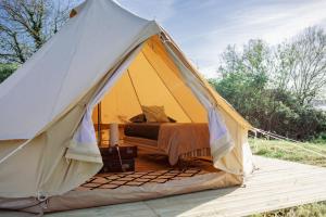 The Glamping Spot - Douarnenez في Plonévez-Porzay: خيمة صفراء مع سرير في حقل