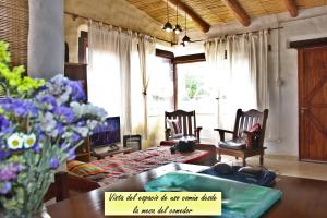 sala de estar con mesa, sillas y flores en CabañaPerchel Tilcara Quebrada de Humahuaca en Huacalera
