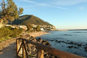 a beach with a wooden fence next to the water at Appartamento Blue in Cala Gonone