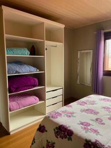 Schlafzimmer mit einem Bett mit rosa und lila Kissen in der Unterkunft Família Cavalli in Gramado