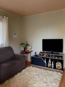 uma sala de estar com um sofá e uma televisão de ecrã plano em Família Cavalli em Gramado