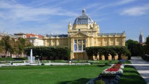 a large building with a fountain in a park at Rooms and Apartments Glossy in Zagreb