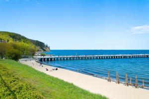 a beach with people sitting on the sand and a pier at Apartament 2-pokojowy Gdynia - Trójmiasto in Gdynia
