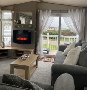 a living room with a couch and a fireplace at Private luxury lodge Hafan y Mor Gwynedd North Wales LL53 6HX in Chwilog