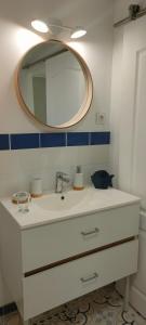 een badkamer met een witte wastafel en een spiegel bij Maison La Thébaïde in Castéra-Lectourois