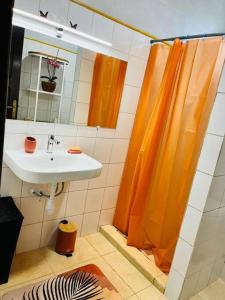 uma casa de banho com uma cortina de chuveiro laranja e um lavatório. em Blue Home2 T3 meublé à Matoury pour 1 à 6 voyageurs. em Matoury