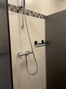 a shower in a bathroom with a hose on the wall at Stadsappartement Valkhof in Nijmegen