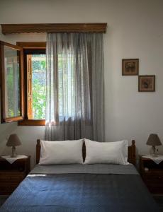 1 dormitorio con 1 cama con ventana y 2 lámparas en Λευκή Καμέλια en Anilio Pelion
