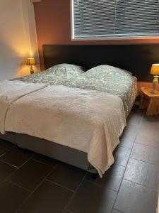 a bed in a bedroom with two tables and a window at Stadsappartement Valkhof in Nijmegen