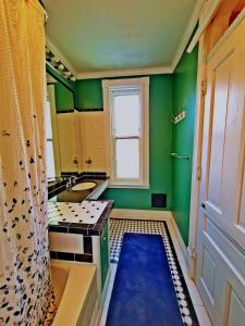 baño con paredes verdes, lavabo y ventana en Point Breeze Guest House en Pittsburgh