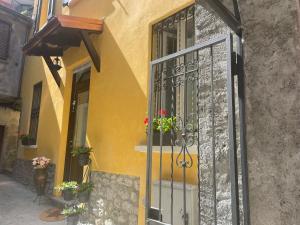 a yellow building with a door and potted plants at Dream Holiday in Argegno