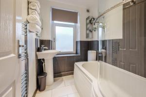 a bathroom with a white tub and a sink at Sleek 2B/1B Retreat in Lindley, Huddersfield in Lindley