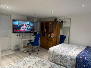 a bedroom with a bed and a flat screen tv at North Avenue, Guest House, Heathrow Airport-Free Parking in Hayes