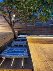 a wooden deck with a tree and blue sleeping mats at Casa de Manu in Rhodes Town