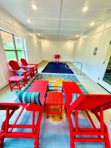 een kamer met een zwembad met rode tafels en stoelen bij New! Indoor Pool/PS 5/Hot tub/Parkway in Pigeon Forge