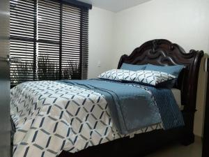 a bed with a blue and white comforter and a window at Grupo Gailla Departamento in Mexico City