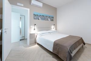 a bedroom with a large white bed with two lamps at Porta del Salento APARTMENT in Brindisi