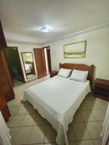 ein Schlafzimmer mit einem großen Bett mit weißer Bettwäsche und Kissen in der Unterkunft Apartamento Sogno D' Estate in Porto Seguro