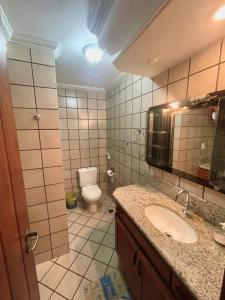 een badkamer met een wastafel, een toilet en een spiegel bij Apartamento Sogno D' Estate in Porto Seguro