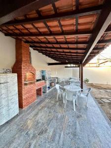 a patio with a table and chairs under a roof at Casa Completa, muito bem localizada ! in Búzios
