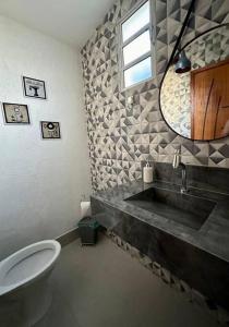 a bathroom with a sink and a toilet and a mirror at Casa Completa, muito bem localizada ! in Búzios