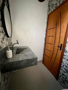 a bathroom with a sink and a wooden door at Casa Completa, muito bem localizada ! in Búzios