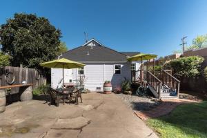 un patio trasero con mesa, sillas y sombrillas en Retro Bungalow en Santa Rosa